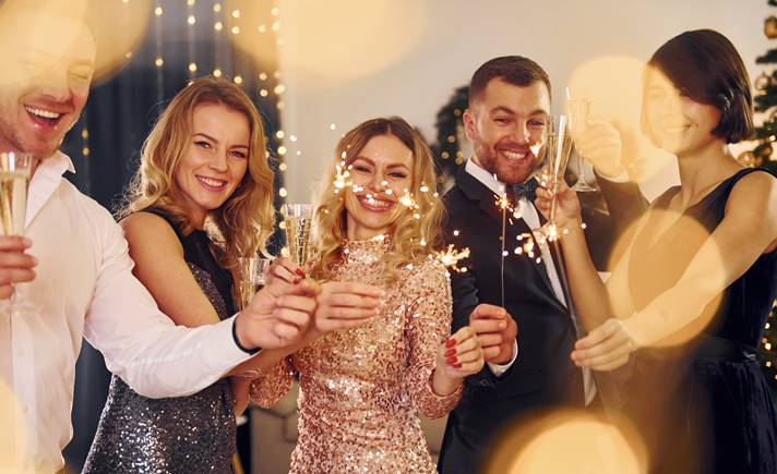 grupo de pessoas celebrando o Ano Novo em um ambiente fechado com sparklers nas mãos